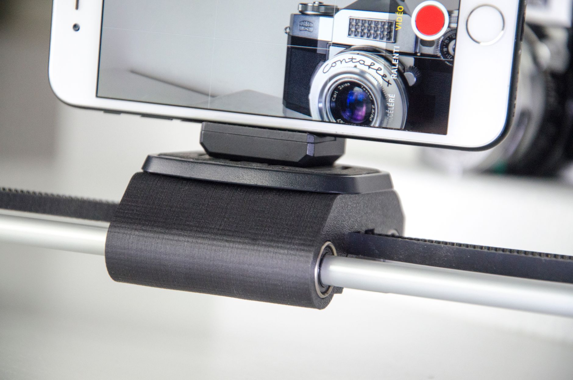 Uno smartphone fissato su un supporto scorrevole mentre riprende una vecchia fotocamera analogica.